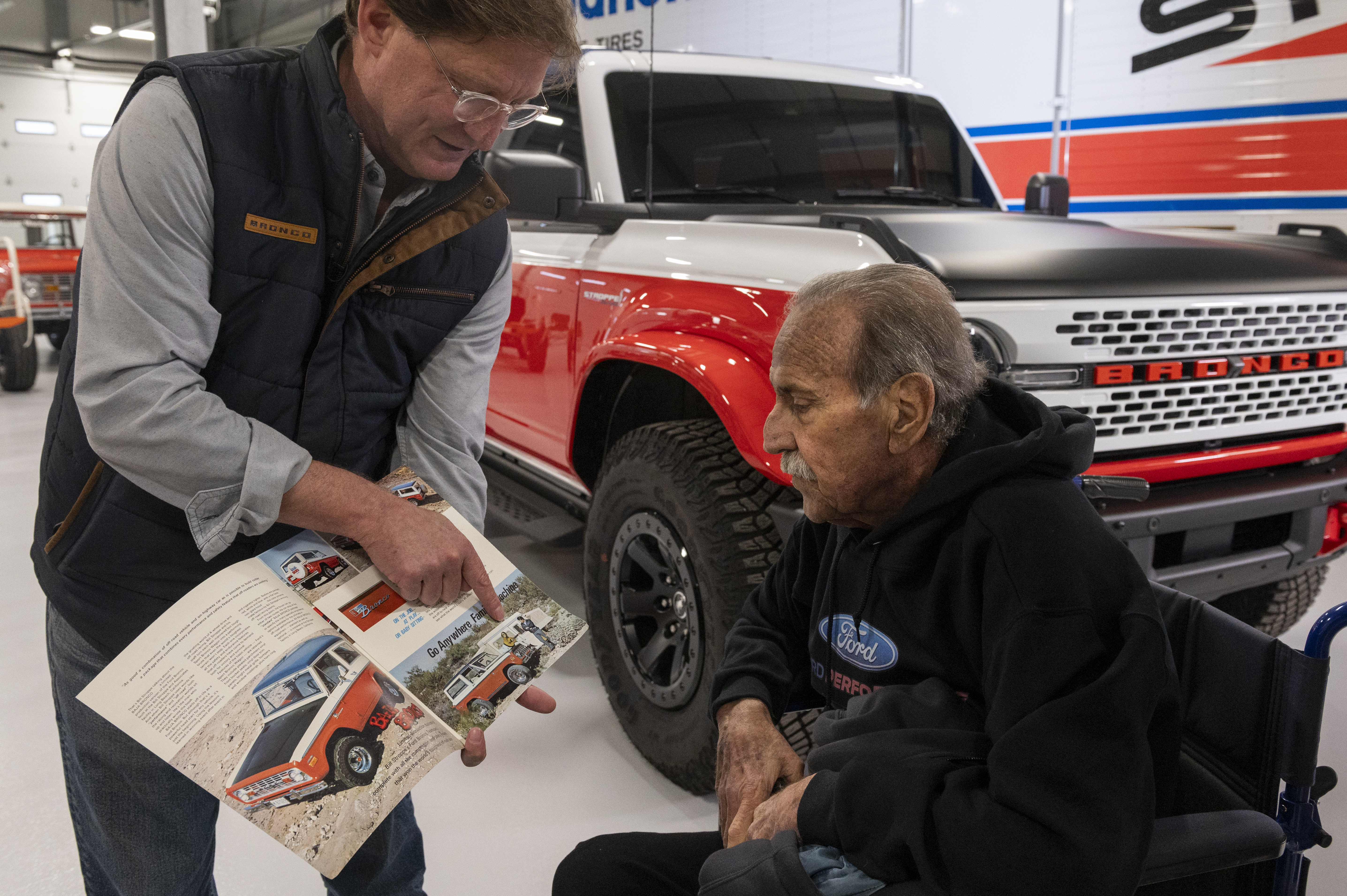 From left, Ted Ryan, archives and heritage brand manager at Ford Motor Co., shows Willie Stroppe historical items and photos while standing next to the new Ford Stroppe Bronco, on Tuesday, Feb. 6, 2024 in Johnstown, Colorado. Rachel Woolf for Ford